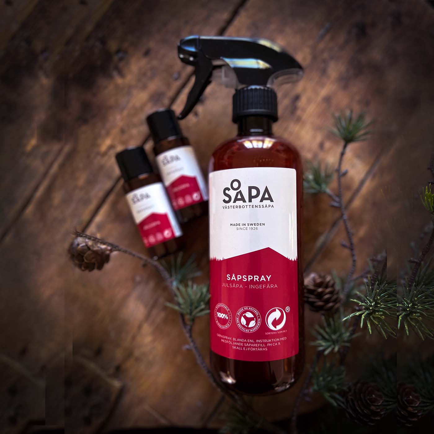 En flaska såpspray med ingefäradoft tillsammans med två refiller, vackert placerade på ett rustikt bord. En naturlig och miljövänlig lösning för effektiv städning.