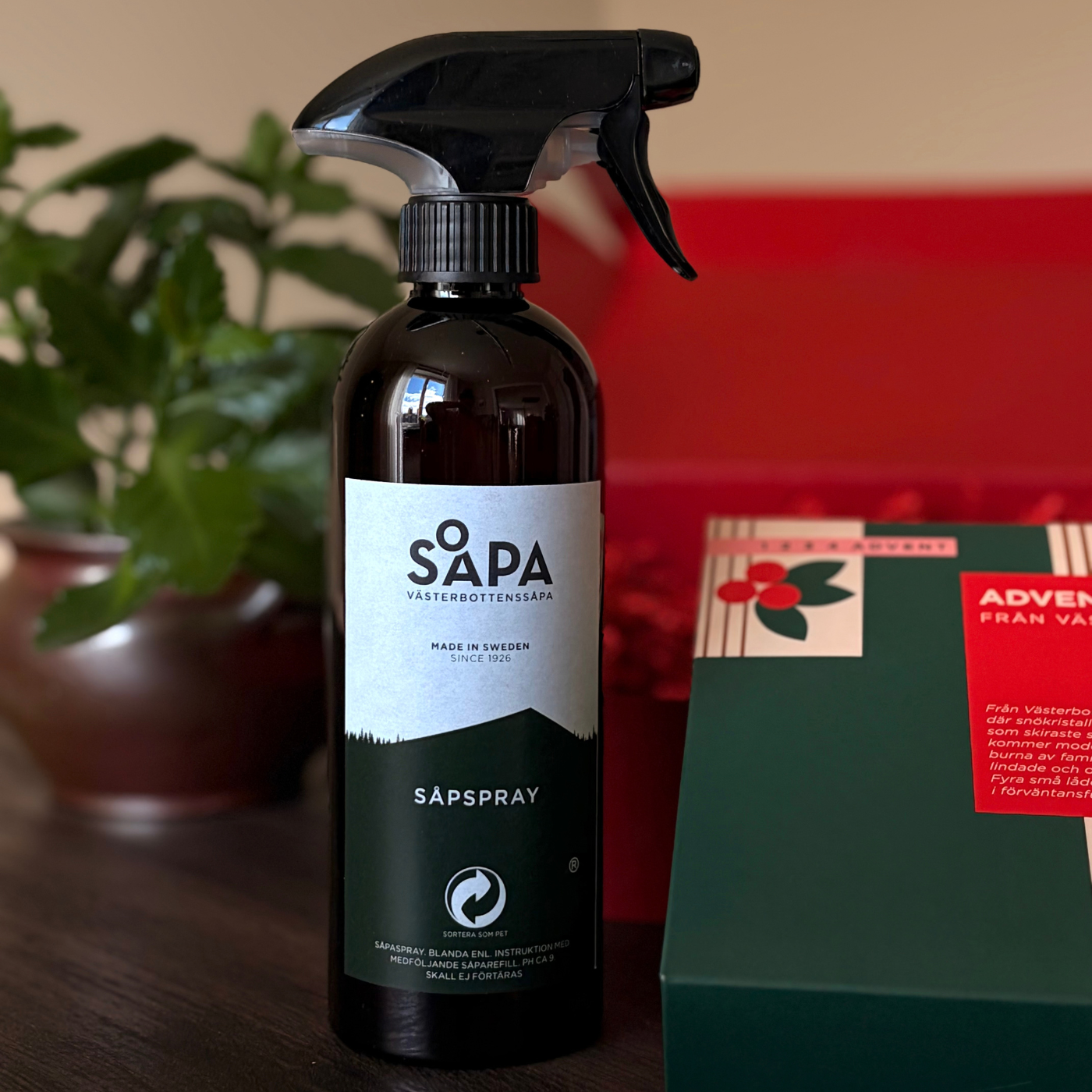Mörk sprayflaska märkt ”Såpspray” från Västerbottenssåpa står bredvid adventskalenderns gröna förpackning.